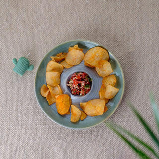 Large light blue round platter with chips and salsa dip on a jute mat, with a cactus candle and leaf. Shop designer tableware Bangalore.