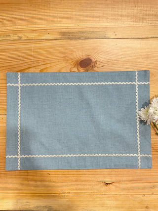 Rectangle blue table mat with silver scallop lace creating a check at the corners, white flowers peeking. Shop home decor online India