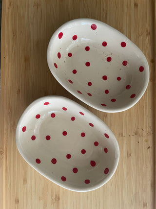 Pair of oval ceramic bowls with red polka dot design on wooden table. Shop tableware for special occasions in India.