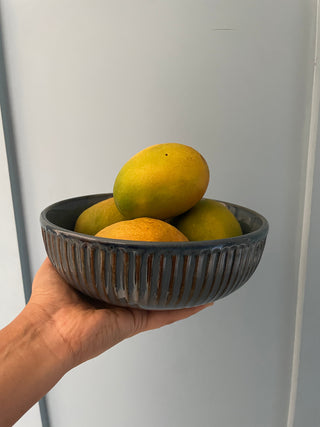 Hand holding blue glazed bowl with ribbed detailing, filled with mangoes as a fruit bowl. Shop luxury ceramics in Bangalore with Oh Yay Project 