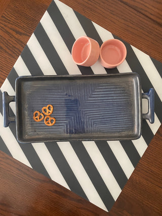 Medium blue ceramic platter with handles, ribbed design, mini pretzels, on B&W stripe mat with 2 small pink dip bowls. Buy designer tableware Bangalore.