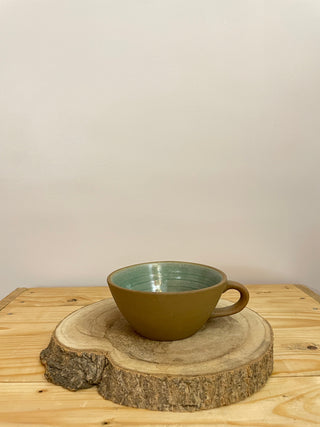 Shop affordable ceramics in Bangalore! Conical ceramic mug with stoneware brown finish outside and green glaze inside, resting on a wooden log.