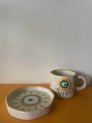 Uneven hem ceramic plate with hand painted evil eye and medium mug with embossed evil eye. Shop artistic ceramic Bangalore