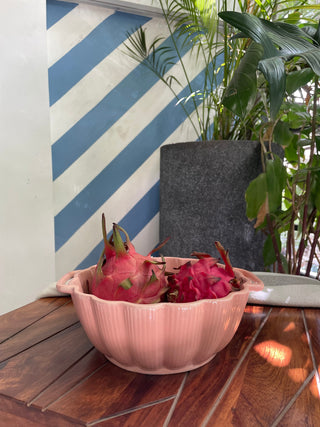 A pretty pink glazed ceramic bowl with handles, scallop rim, filled with dragon fruits on a table. Buy designer tableware in Bangalore.