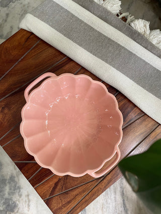 Top view of pink ceramic bowl on wooden table, resembling a large flower with scallop edges and handles. Buy kitchenware in Bangalore.