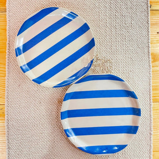 Set of 2 uneven hem ceramic plates with off-white base and blue stripe detailing on jute runner. Shop tableware online in India.